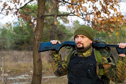 Soldier with a rifle in the autumn forest