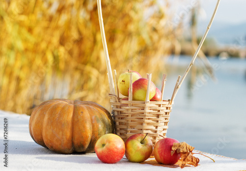 Pumpkin and basket with apples on table