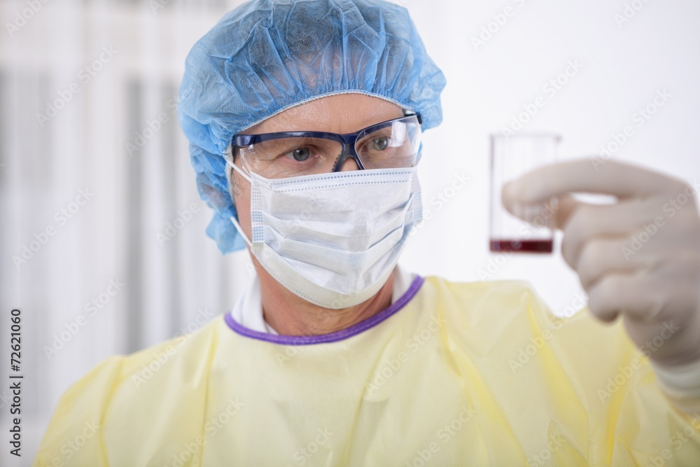 doctor in protective gear holding blood sample