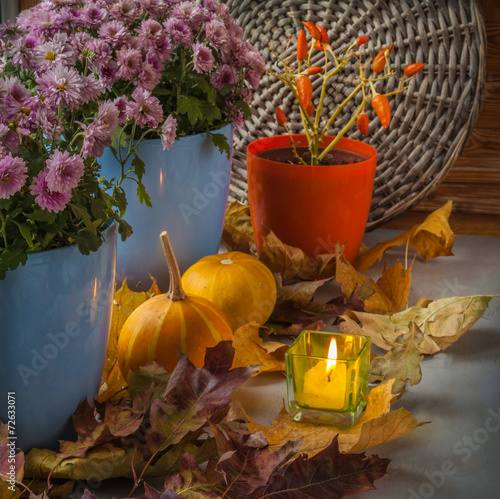 Pumpkin and chrysanthemum next to a lit candle before