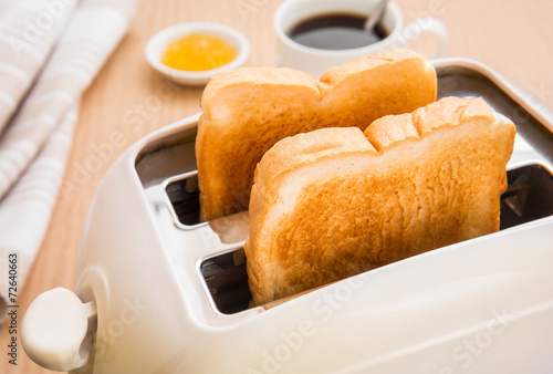 Bread slices in toaster with coffee and jam