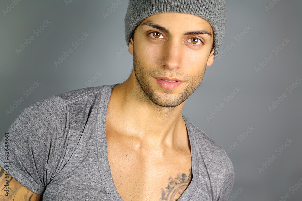 young attractive man with a hat on a gray background young attractive man with a hat on a gray background