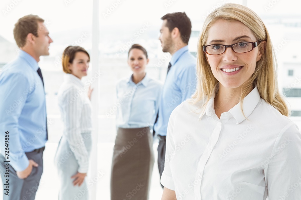 Businesswoman with colleagues behind at office Businesswoman with colleagues behind at office