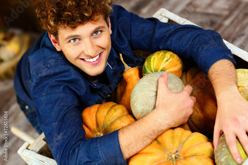Smiling man hugging pumpkins