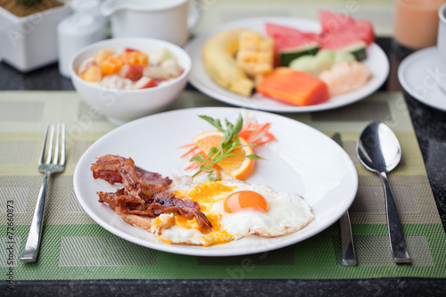 Hotel breakfast. Fried eggs with bacon and fruit
