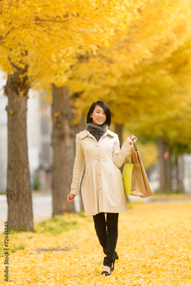 秋の歩道を歩く女性