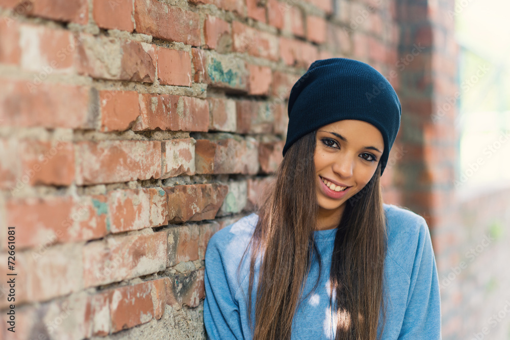 Smiling teenager portrait outdoors against brick wall.