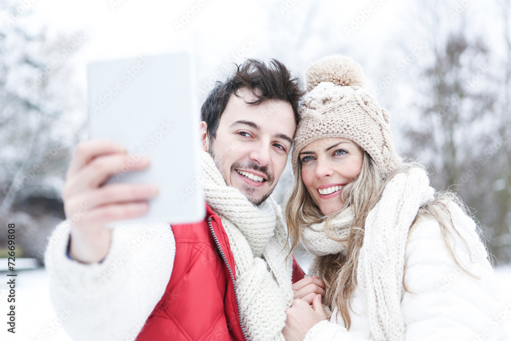 Paar im Winter fotografiert sich mit Tablet PC