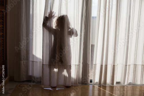 Tableau sur toile silhoutte of a child waving through curtains