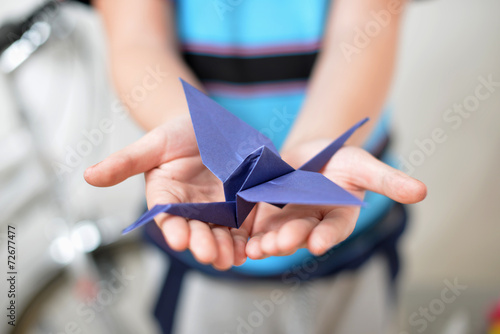 Origami crane in children's hands (soft focused)