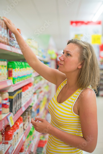 Young woman choosing pasta in grocery store.