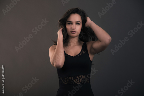 Cute brunette teenage girl with hands in hair wearing black dres