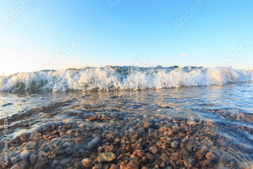 Wave with foam closeup view at sunset