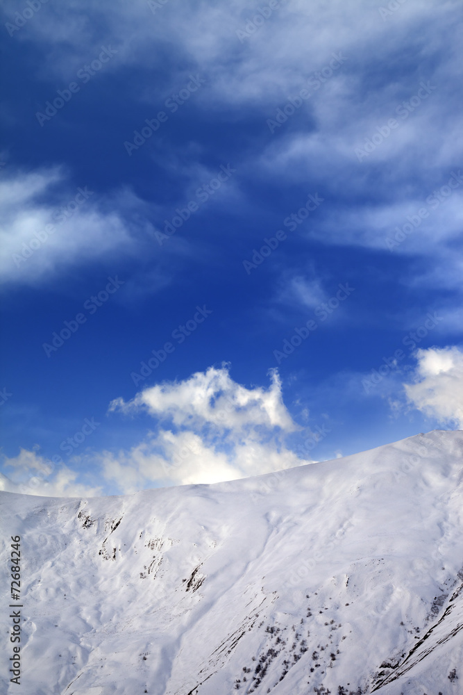 Off-piste slope and blue sky with clouds