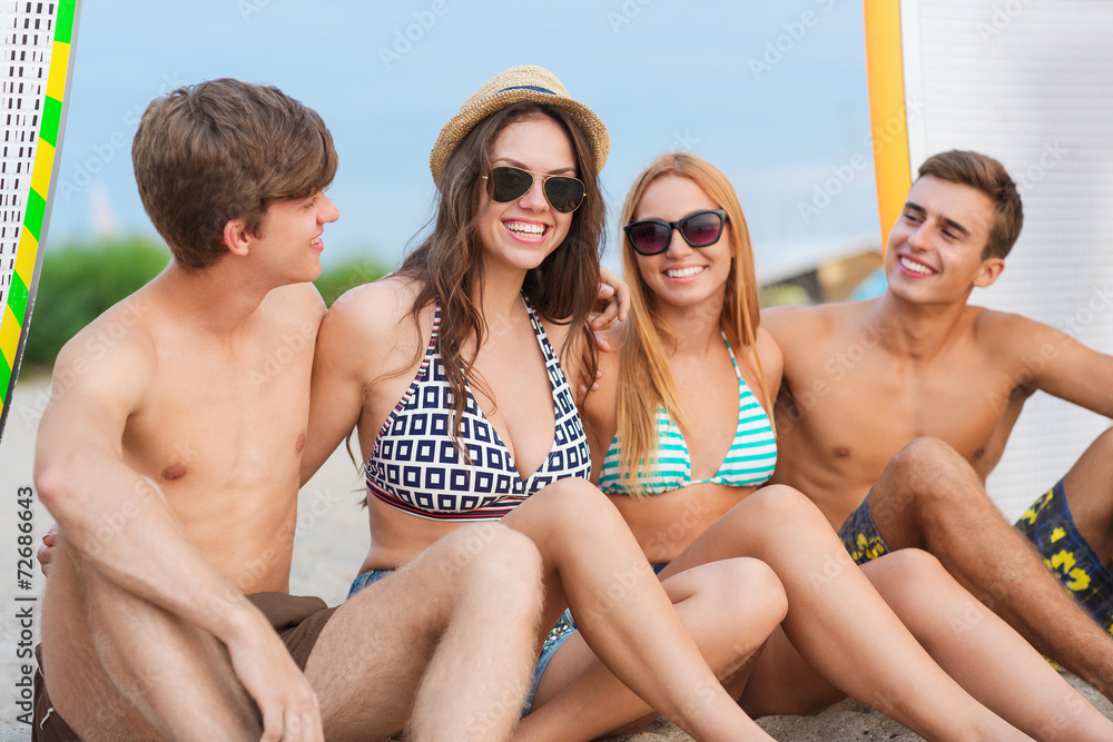 smiling friends in sunglasses with surfs on beach