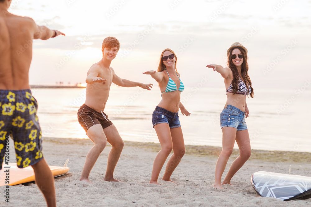 smiling friends in sunglasses with surfs on beach