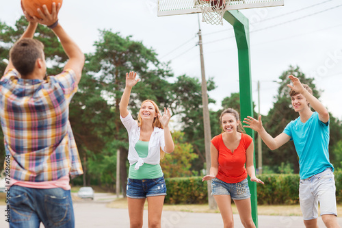 group of smiling teenagers playing basketball © Syda Productions