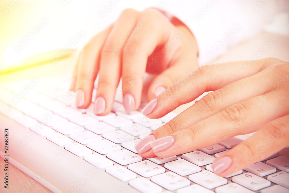 Female hands typing on keyboard on light background Female hands typing on keyboard on light background