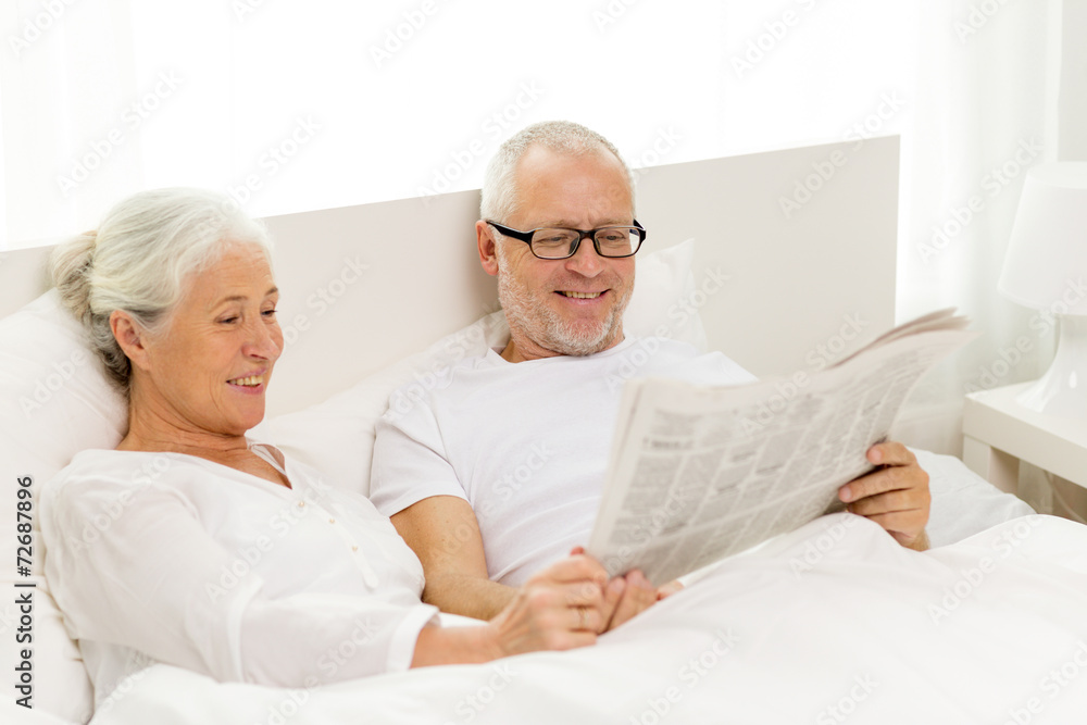 happy senior couple with newspaper in bed happy senior couple with newspaper in bed