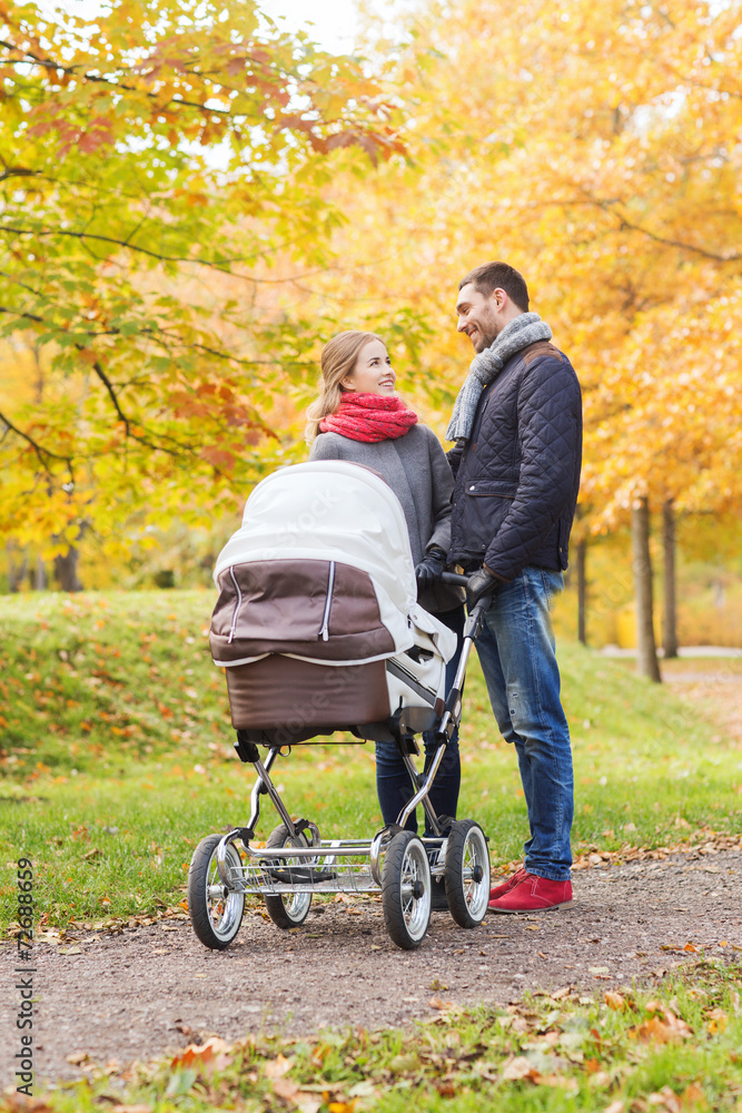 smiling couple with baby pram in autumn park smiling couple with baby pram in autumn park