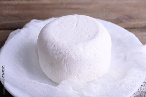 Cottage cheese on gauze on plate on wooden background