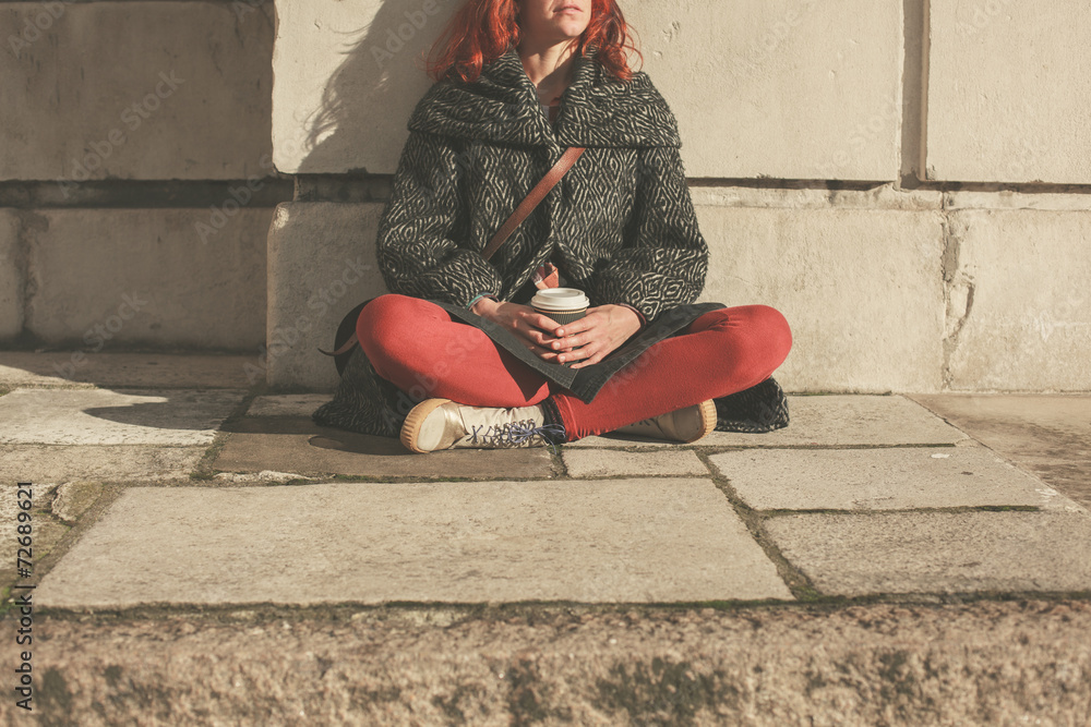 Fototapeta premium Young woman sitting in the street with coffee