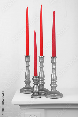 Red candles in candle holders on table on white background