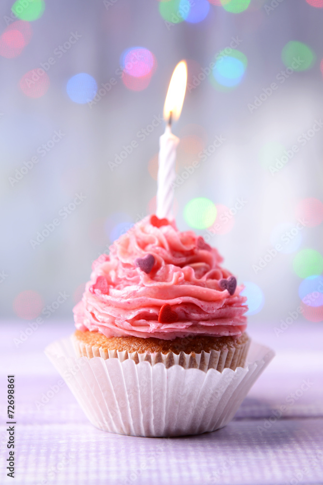 Delicious birthday cupcake on table on light background