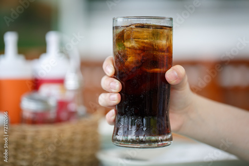 Hand holding glass of cola drink
