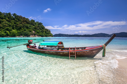 Long tail boat on white sand beach on tropical island