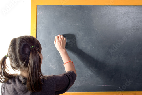 Tableau sur toile a little girl with pigtails writes on a blackboard