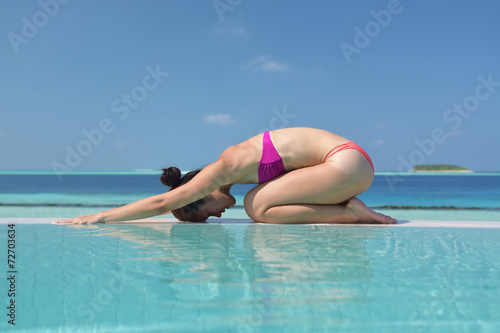 Asian chinese woman practising yoga by the sea