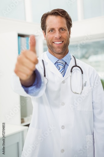 Smiling male doctor gesturing thumbs up at medical office