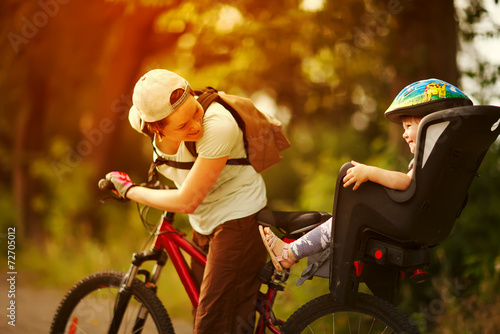 Young woman on a bicycle with little daughter  behind