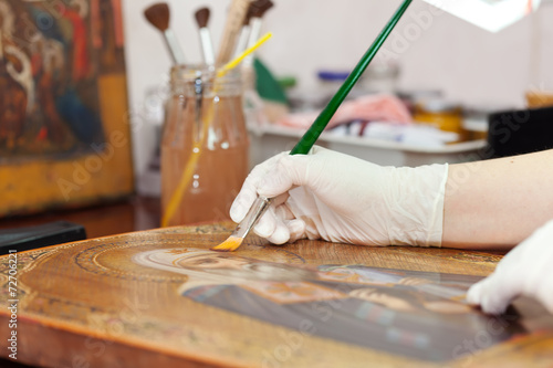 Art restorer works on ancient gilded icon
