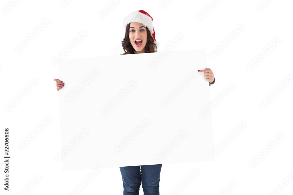 Pretty brunette in santa hat pointing white poster Pretty brunette in santa hat pointing white poster