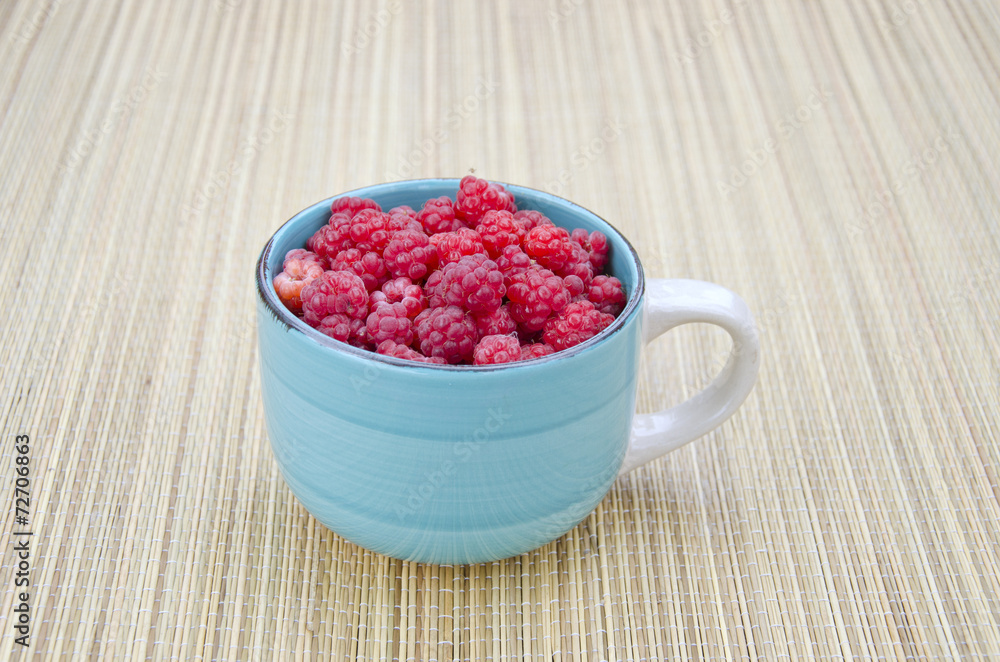 fresh raspberry fruits in blue ceramic cup