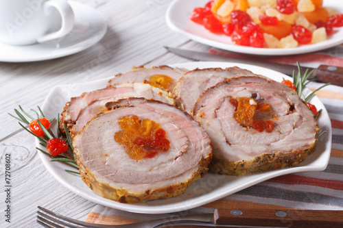 Pork roll with apricot and cherry closeup on a plate.