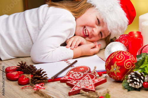 Funny girl in Santa hat writes letter to Santa near christmas de