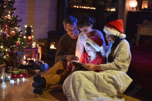 lovely family sharing digital tablet near the wood stove on a wi