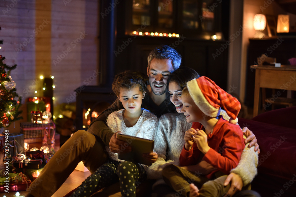 lovely family sharing digital tablet near the wood stove on a wi