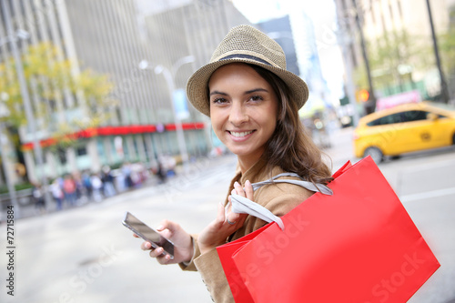 Canvas Print Shopping girl with red bag and smartphone in Manhattan