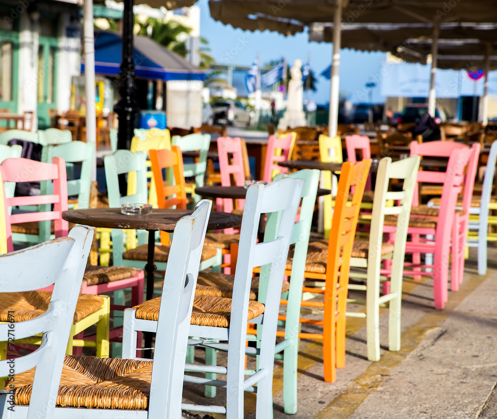 Greek island restaurants with colorful tables and chairs. - obrazy, fototapety, plakaty 
