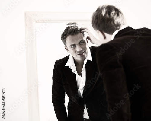 Stylish sexy man checking his hairstyle in mirror