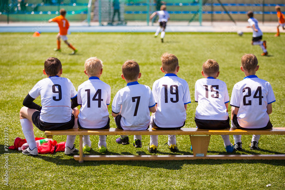 Football soccer match for children. Kids waiting on a bench. - obrazy, fototapety, plakaty 