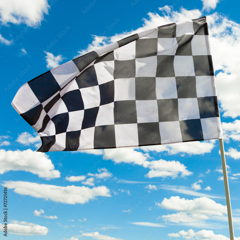 Checkered flag against the blue sky with clouds