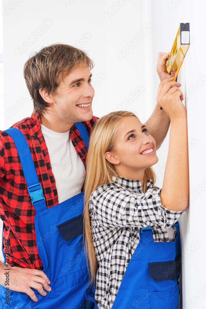 Repairman helping woman to use builder level Repairman helping woman to use builder level