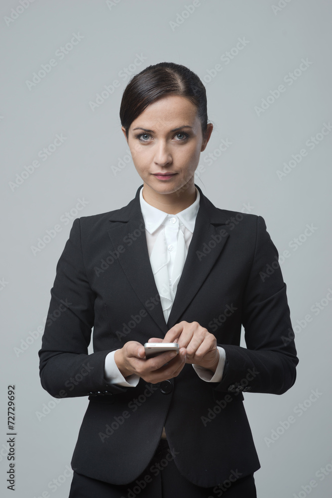 Smiling confident businesswoman using touch screen mobile phone Smiling confident businesswoman using touch screen mobile phone