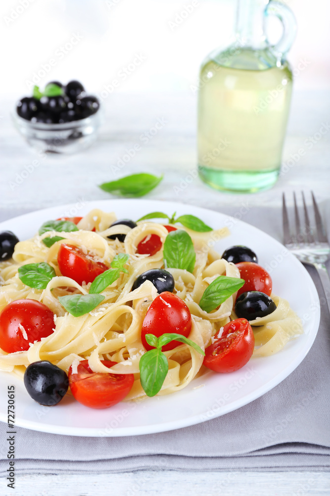 Spaghetti with tomatoes, olives and basil leaves