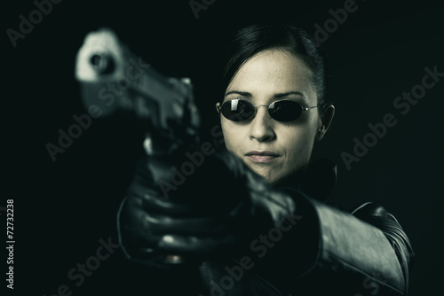 Attractive female criminal pointing a gun